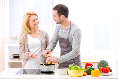 View of a Young attractive man helping out his wife while cookingの写真素材