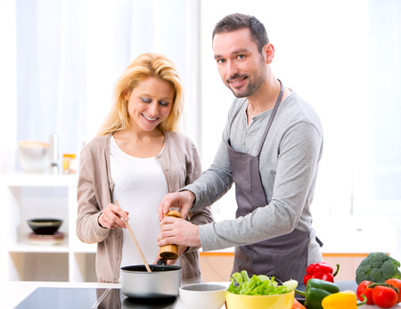 View of a Young attractive man helping out his wife while cookingの写真素材