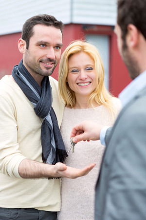 View of a Real estate agent delivers keys to young atractive coupleの写真素材