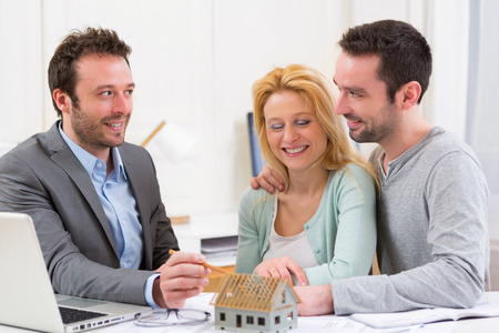 View Real estate agent present project on miniature house to a young coupleの写真素材