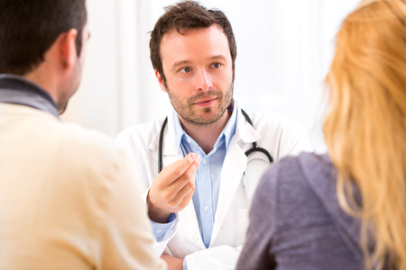 View of a Young attractive doctor advising a young couple of patientsの写真素材
