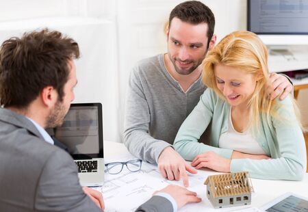 View of a Real estate agent present project on blueprint to a young coupleの写真素材