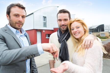 View of a Real estate agent delivers keys to young atractive coupleの写真素材