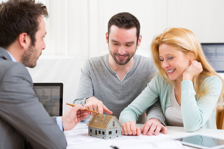 View of a Real estate agent present project on miniature house to a young coupleの写真素材