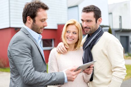View of a Real estate agent and a young couple in front of their next homeの写真素材