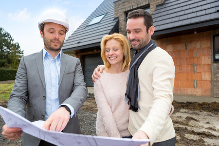 View of a Real estate agent and a young couple in front of future homeの写真素材