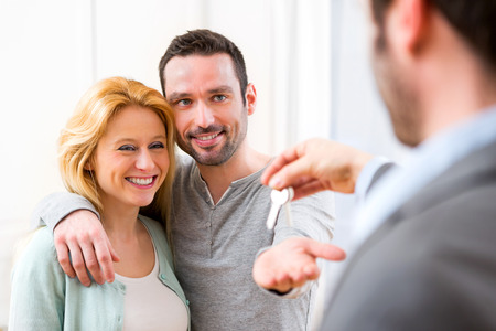 View of Real estate agent delivers keys of new house to young coupleの写真素材