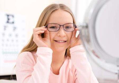 VIew of a Young little girl trying glasses at the opticianの写真素材