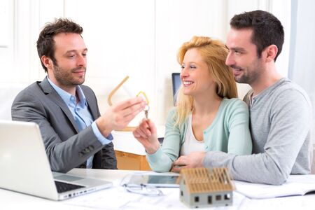 View of a Real estate agent delivers keys of new house to young coupleの写真素材