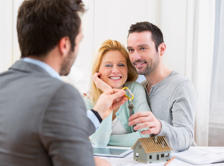 View of a Real estate agent delivers keys of new house to young coupleの写真素材