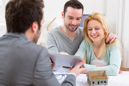 View of a Real estate agent present project on tablet to a young coupleの写真素材