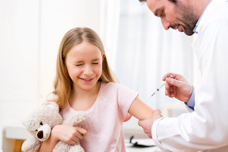 View of a Young little girl  being vaccinated at the doctorの写真素材