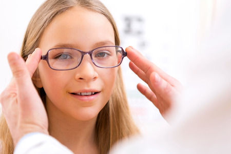 VIew of a Young little girl trying glasses at the opticianの写真素材