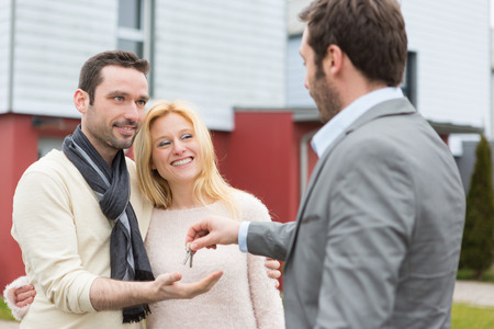 View of a Real estate agent delivers keys to young atractive coupleの写真素材