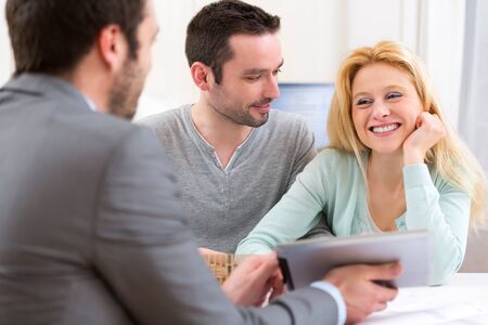 View of a Real estate agent present project on tablet to a young coupleの写真素材