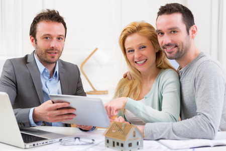 View of a Real estate agent present project on tablet to a young coupleの写真素材
