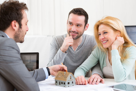 View of a Real estate agent present project on miniature house to a young coupleの写真素材