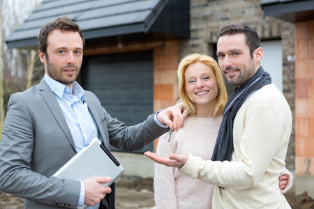 View of a Real estate agent delivers keys to young atractive coupleの写真素材