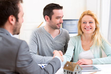 View of a Young happy couple handshaking real estate agent after signing contractの写真素材