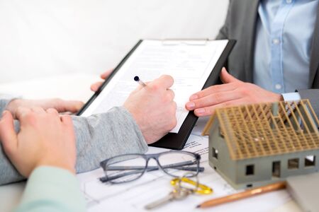 Detailed view of hand signing contract at a real estate agent office