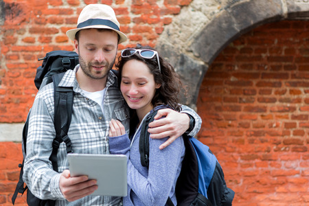 View of a Young couple of tourists using tablet to visit cityの写真素材