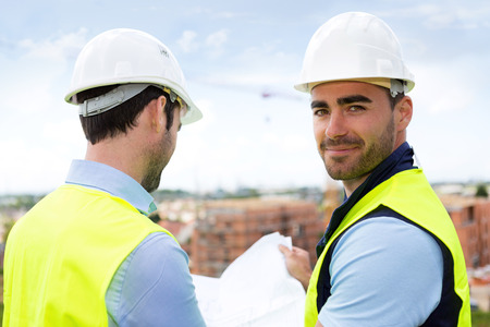 View of a Engineer and worker watching blueprint on construction site