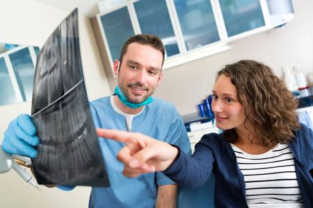 View of a Young attractive dentist showing x-ray to patientの写真素材