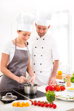 View of a Young chef training a young attractive girl to cookの写真素材
