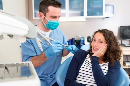 View of a Young attractive woman scared to being cured by a dentistの写真素材