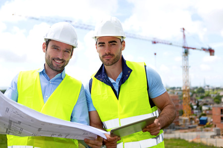 View of a Engineer and worker watching blueprint on construction siteの写真素材