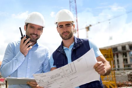 View of an Engineer and worker checking plan on construction siteの写真素材