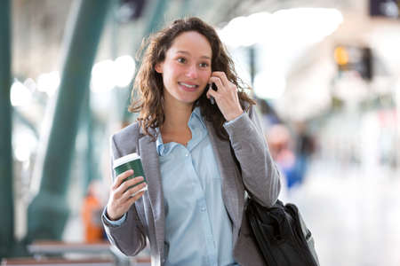 View of a Young attractive business woman using smartphone drinking coffeeの写真素材