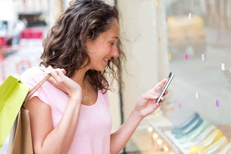 View of a Young attractive woman using mobile during shoppingの写真素材