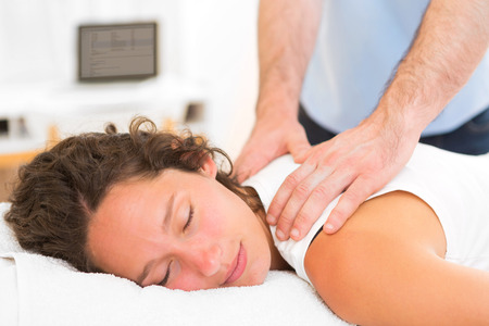 View of a Young attarctive woman being manipulated by physiotherapistの写真素材