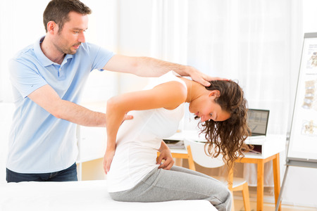 View of an Young attractive woman being manipulated by physiotherapistの写真素材