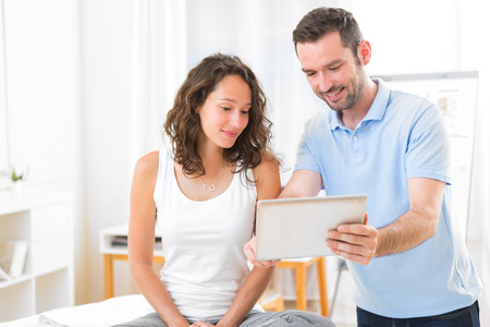 View of a Young attractive physiotherapist using tablet with patientの写真素材