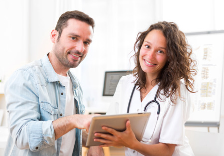 View of a Young doctor showing results on tablet to patientの写真素材