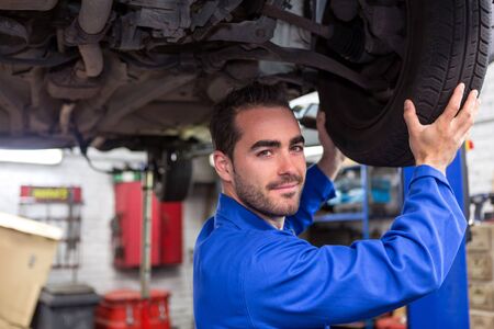 View of a Young attractive mechanic working on a car at the garageの写真素材