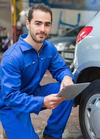 View of a Young attractive mechanic working on a car at the garageの写真素材