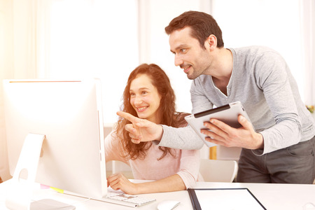 View of a Man working with his co-worker on computerの写真素材
