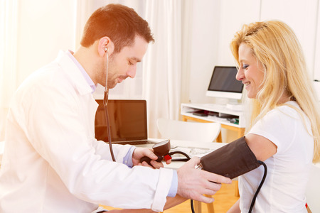 View of a Young attractive doctor checking patient's blood pressureの写真素材
