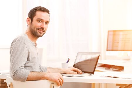 View of a Young smiling man in front of a computerの写真素材