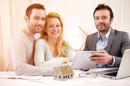 View of a Real estate agent present project on tablet to a young coupleの写真素材