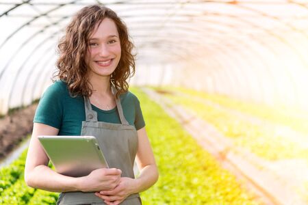 View of a Portrait of an attractive farmer in a greenhouse using tabletの写真素材