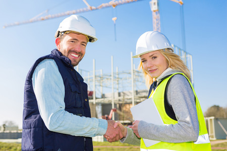 View of an architect and worker handshaking on construction siteの写真素材