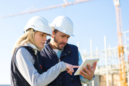View of Two workers working outside with a tablet on a construction siteの写真素材