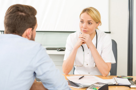 View of a Young attractive woman doctor listening his patientの写真素材