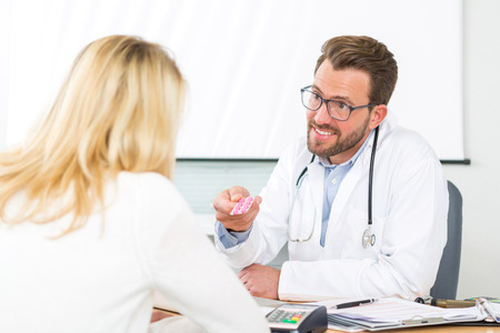 View of a Young attractive doctor giving pills to a patientの写真素材
