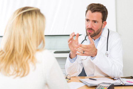 View of a Young attractive doctor listening his patientの写真素材