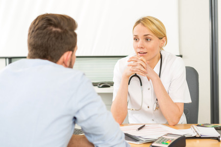 View of a Young attractive woman doctor listening his patientの写真素材